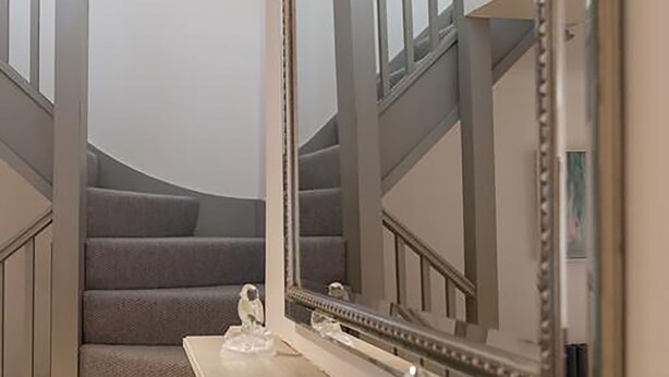 A staircase with a mirror and a vase on a console table. - Linnet House, Shropshire (Ludlow)