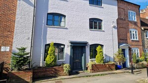 A two-story building with a white brick facade, multiple windows, and a dark-colored entrance door. - Linnet House, Shropshire (Ludlow)