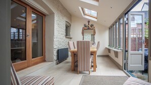 A dining area with a table and chairs, a large mirror, and a view of the outside. - Linnet House, Shropshire (Ludlow)