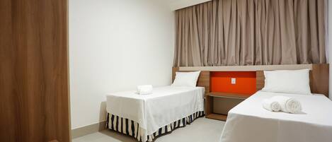 A hotel room with two beds, a wooden panel on one side, and a large window with curtains.