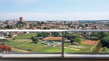 A balcony with a view of a cityscape, including residential buildings and a sports complex.