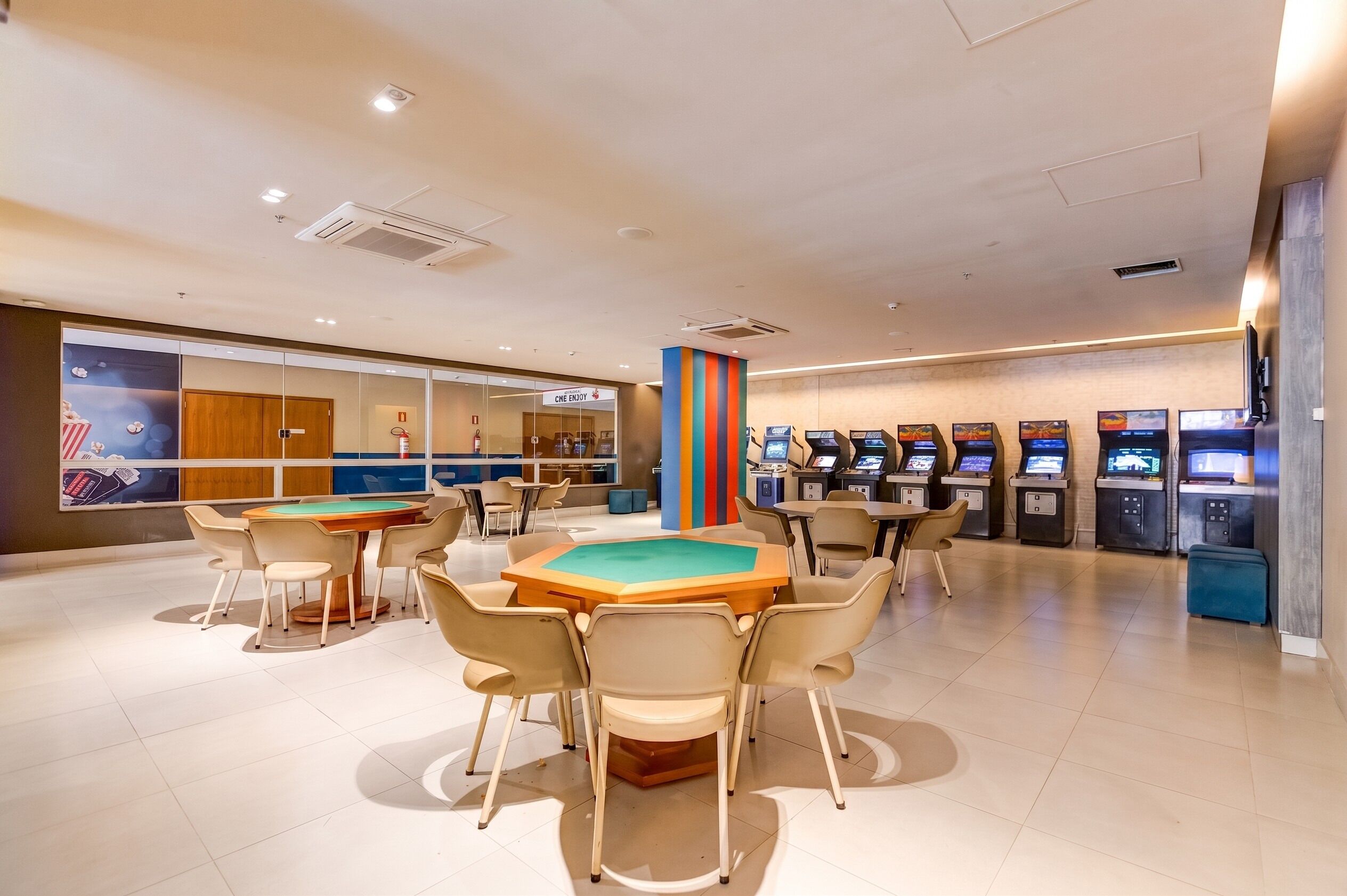 A spacious indoor area with a pool table, multiple gaming machines, and a seating area with chairs.