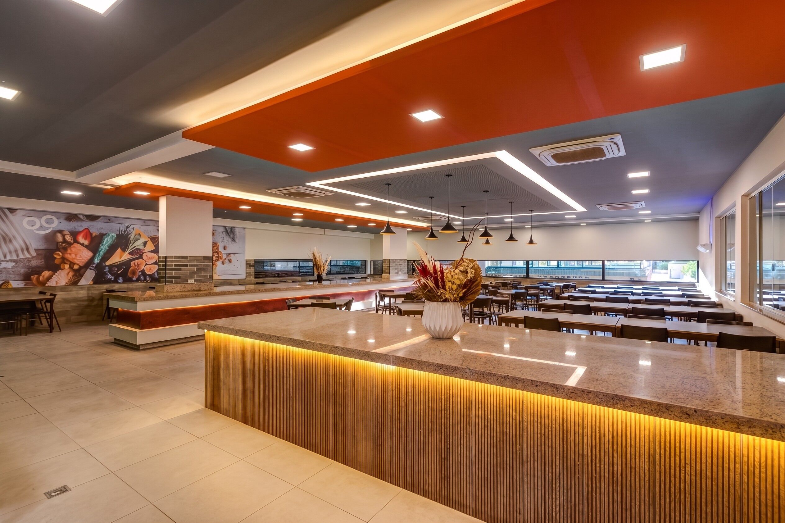 A modern restaurant with a central island, seating area, and a mural on the wall.