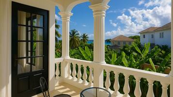A balcony with white balustrades, a black door, and a glass table.