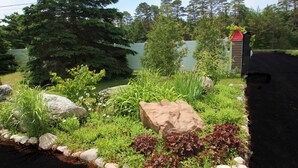 A landscaped garden with a variety of plants, rocks, and a shed. - Mackinac Lake Trail Motel (Mackinaw City)