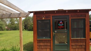 A wooden structure with a neon sign reading "coffee" and a door. - Mackinac Lake Trail Motel (Mackinaw City)