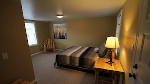 A bedroom with a bed, a chair, a lamp, and a painting on the wall. - Mackinac Lake Trail Motel (Mackinaw City)