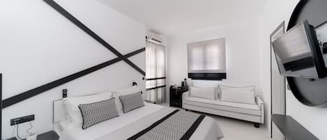 Ett modernt hotellrum med en stor säng, en soffa, en TV och ett skrivbord.