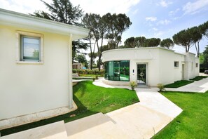 A modern two-story house with a curved glass facade, a small front yard, and a pathway leading to the entrance. - Suite  Testani (Frosinone)