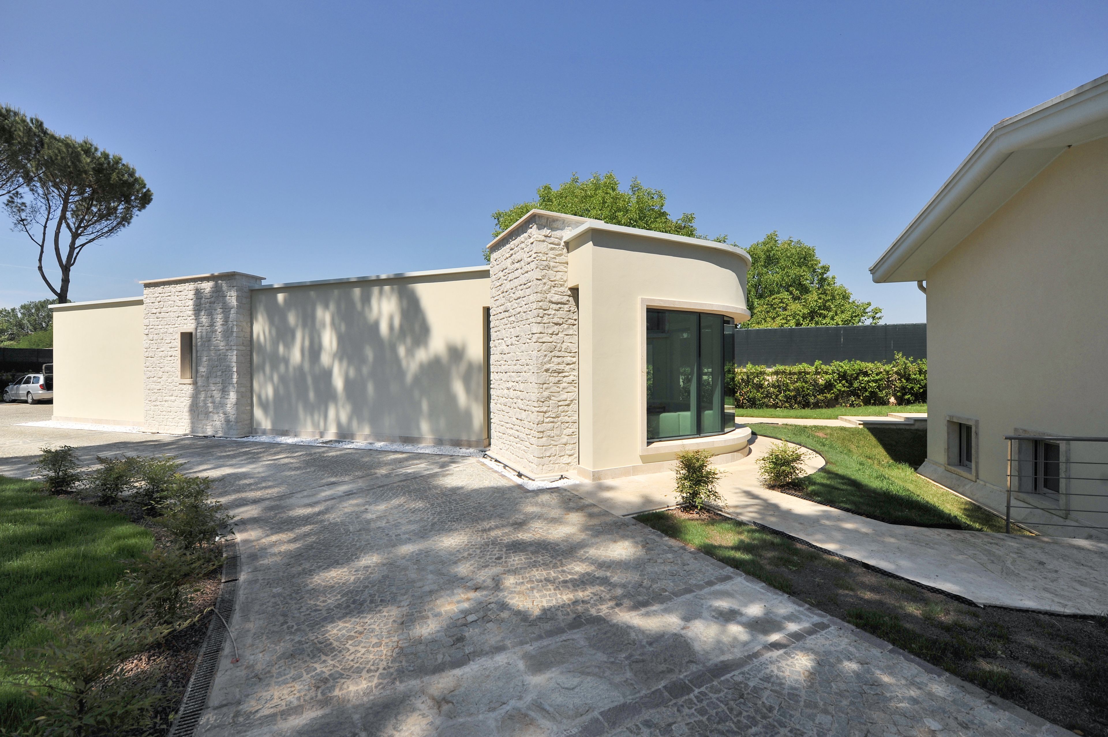 A modern building with a stone facade, a curved driveway, and a well-maintained lawn.