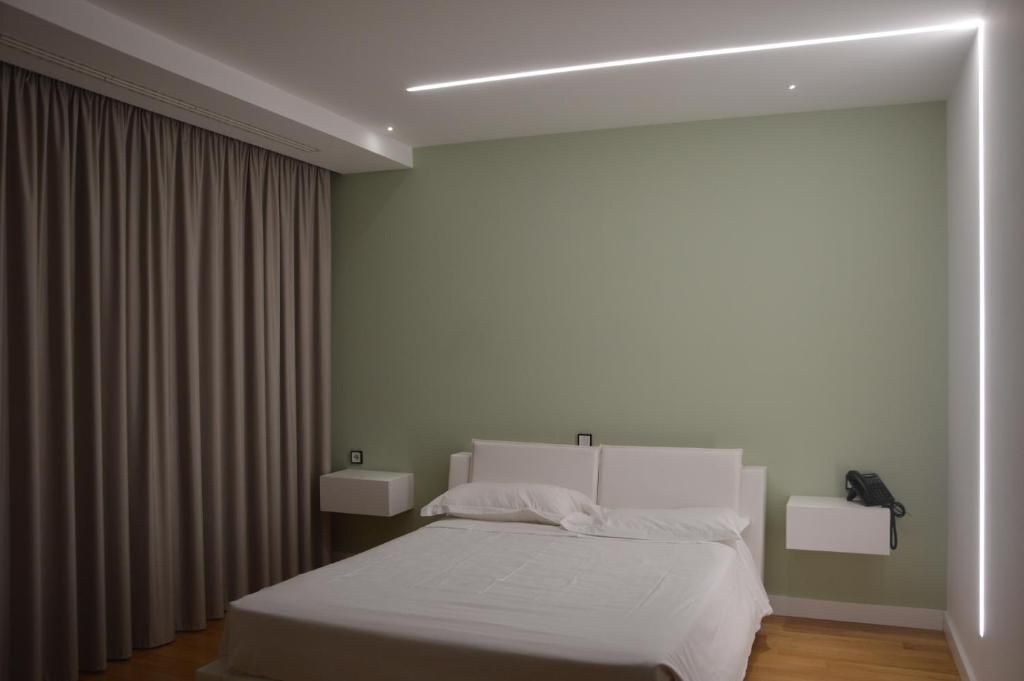 Una habitación de hotel con una cama, mesitas de noche, un teléfono y una cortina.