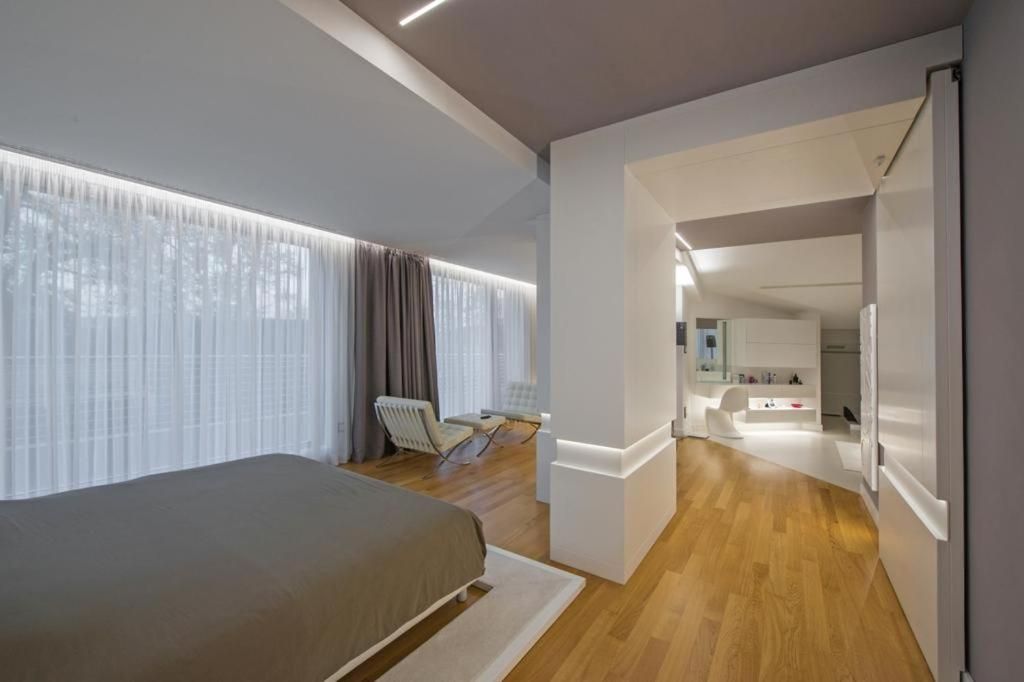 A modern hotel room with a large bed, a seating area, and a separate bathroom.