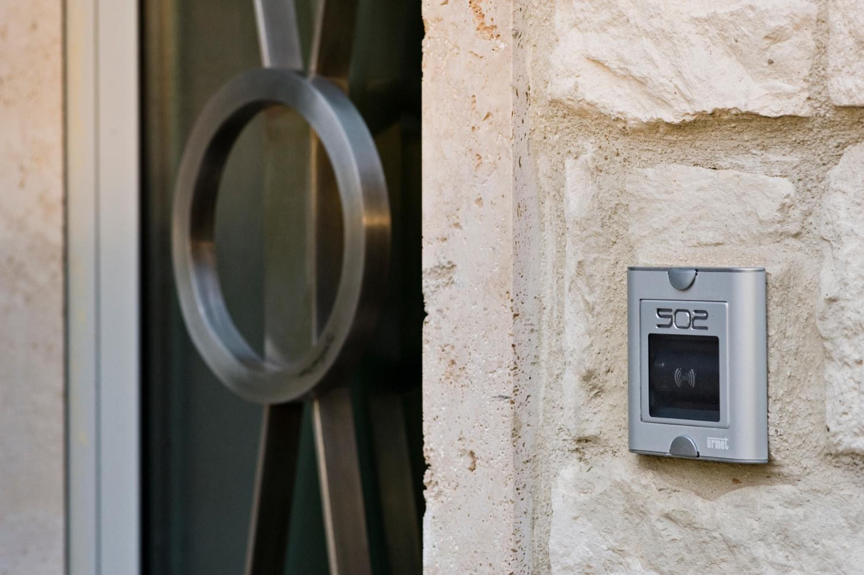 Una puerta con manija circular y un intercomunicador instalado en la pared, etiquetado como '502'.