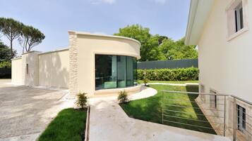 A modern house with a curved facade, a stone accent wall, and a glass door leading to a covered patio.