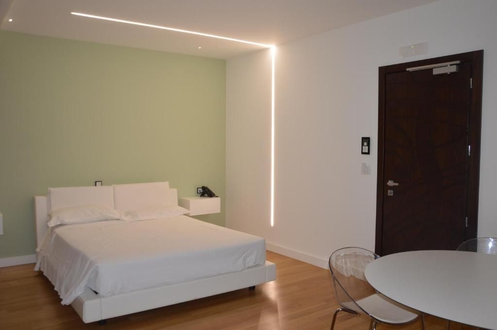 A modern bedroom with a bed, bedside table, and a round table with chairs.
