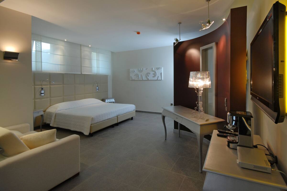 Une chambre d’hôtel avec un lit, un bureau, une chaise, une télévision et une lampe.
