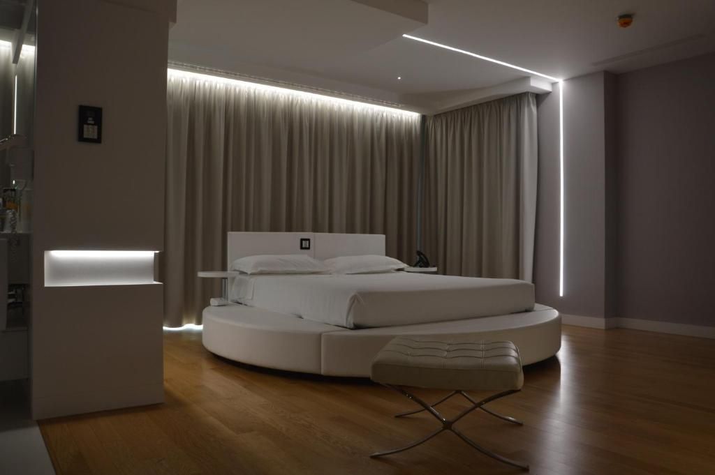 Une chambre à coucher moderne avec un lit rond, une table de chevet et un banc.