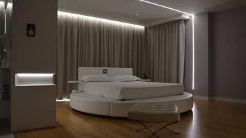 Une chambre à coucher moderne avec un lit rond, une table de chevet et un banc.
