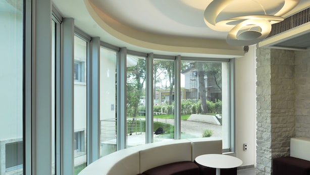 Un interior moderno con una zona de estar curvada, ventanas amplias y una lámpara de techo original.