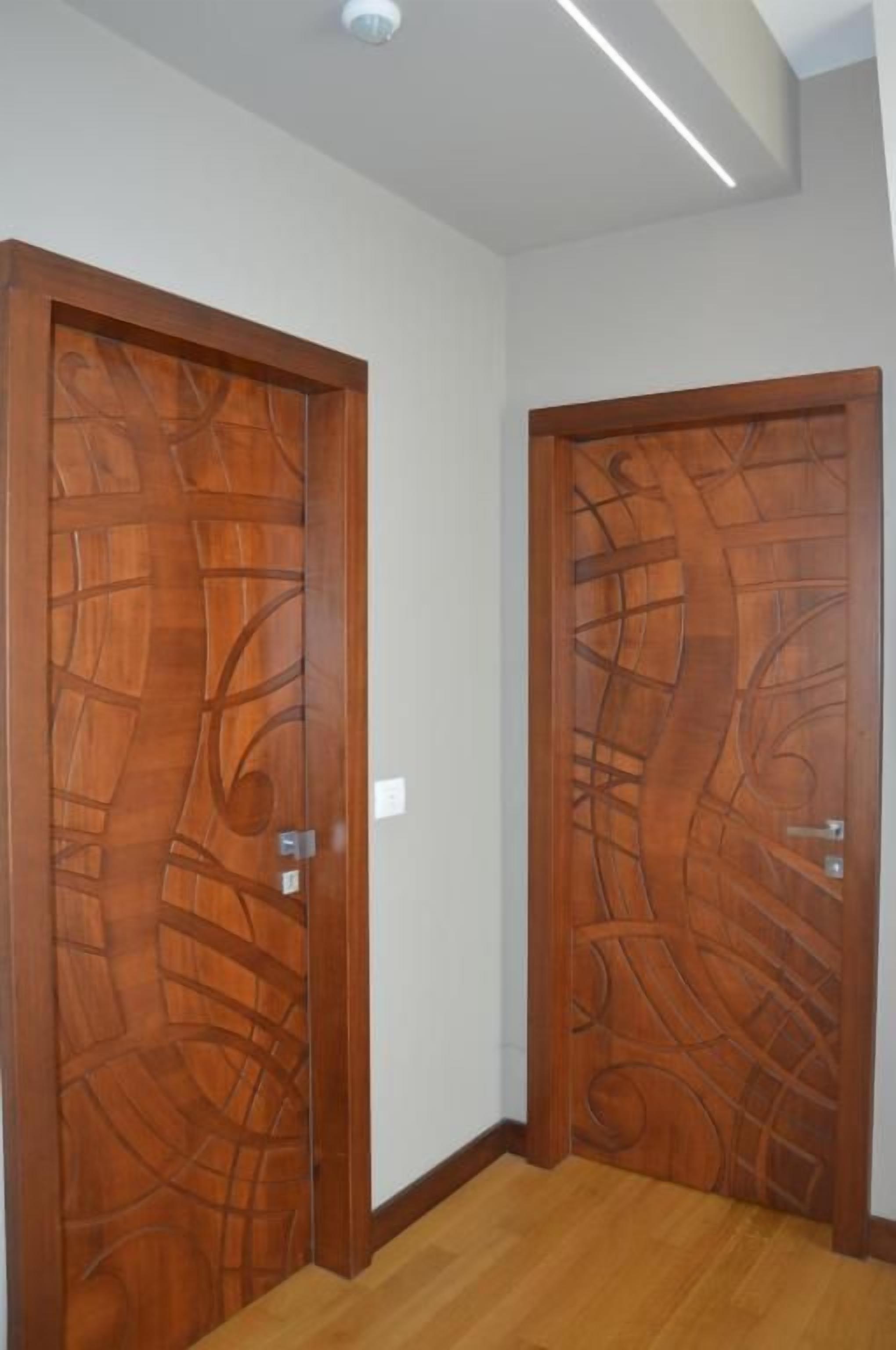 A hallway with two wooden doors featuring intricate designs.