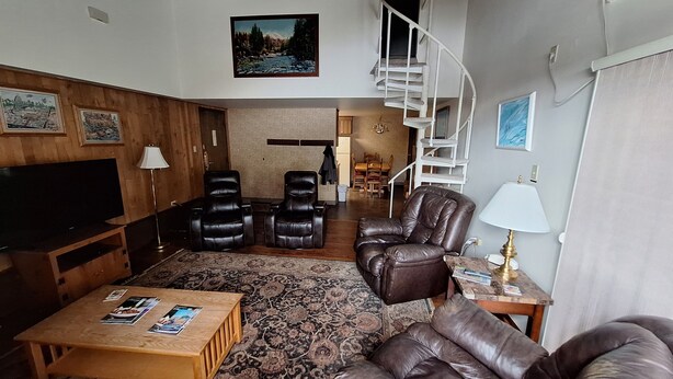 A living room with a TV, leather chairs, a sofa, a coffee table, and a staircase. - Gondola Square, only 60 feet to the gondola. Best location. (Steamboat Springs)