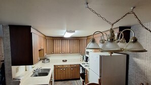 A compact kitchen with wooden cabinets, a central island, and a dining table. - Gondola Square, only 60 feet to the gondola. Best location. (Steamboat Springs)