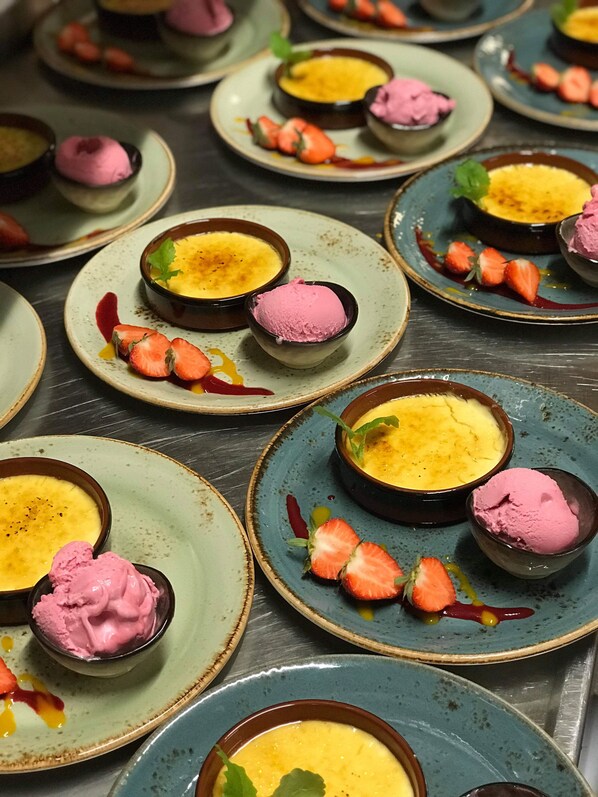 Una presentación de postres con múltiples platos de natillas y helado rosa, adornada con fresas y hojas de menta.