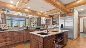 A spacious kitchen with wooden beams, granite countertops, and a stainless steel refrigerator. - Nearby River Run and the Gondola, Covered Patio w/Hot Tub, Media/Game Room (Keystone)