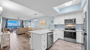 Une cuisine moderne avec des meubles blancs, des appareils en acier inoxydable et un grand îlot central.