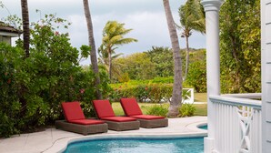 A poolside area with wicker lounge chairs and a white railing. - BREATHTAKING : on water front with panoramic views + pool + dock (Harbour Island)
