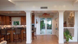 A spacious kitchen with a central island, bar stools, and a dining area with chairs. There is a large fish decoration above the sliding glass doors leading to a patio. - BREATHTAKING : on water front with panoramic views + pool + dock (Harbour Island)