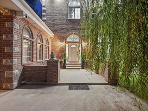 A brick building with a stone lion statue, a covered entrance, and a concrete driveway.