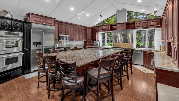 Una cocina moderna con armarios de madera oscura, electrodomésticos de acero inoxidable y una isla grande con taburetes de bar.