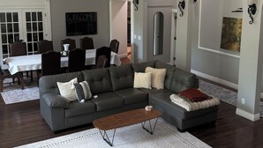 Una sala de estar con un sofá modular, una mesa de centro y un comedor con una mesa y sillas.