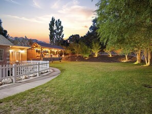 A well-maintained outdoor area with a wooden deck, a covered seating area, and a grassy lawn.