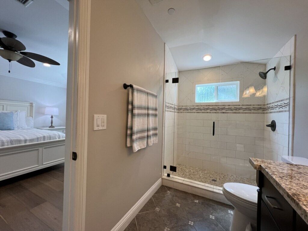 Une salle de bain avec une douche, des toilettes et une serviette accrochée au mur.