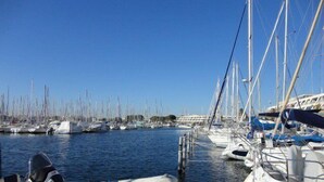 Un port de plaisance où de nombreux bateaux sont amarrés, le ciel est dégagé et l’eau est calme.