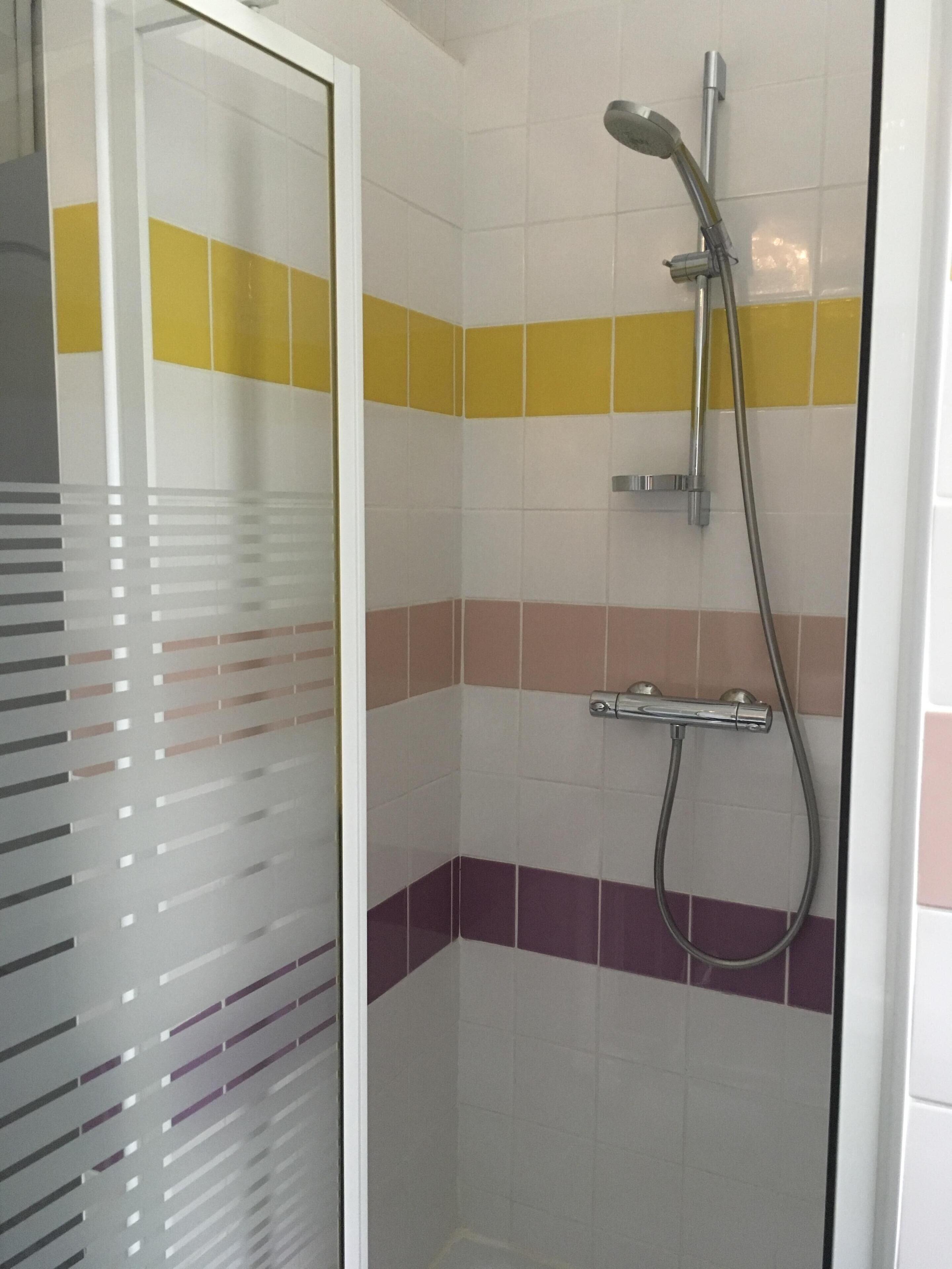 A shower area with a glass door, tiled walls, and a showerhead.