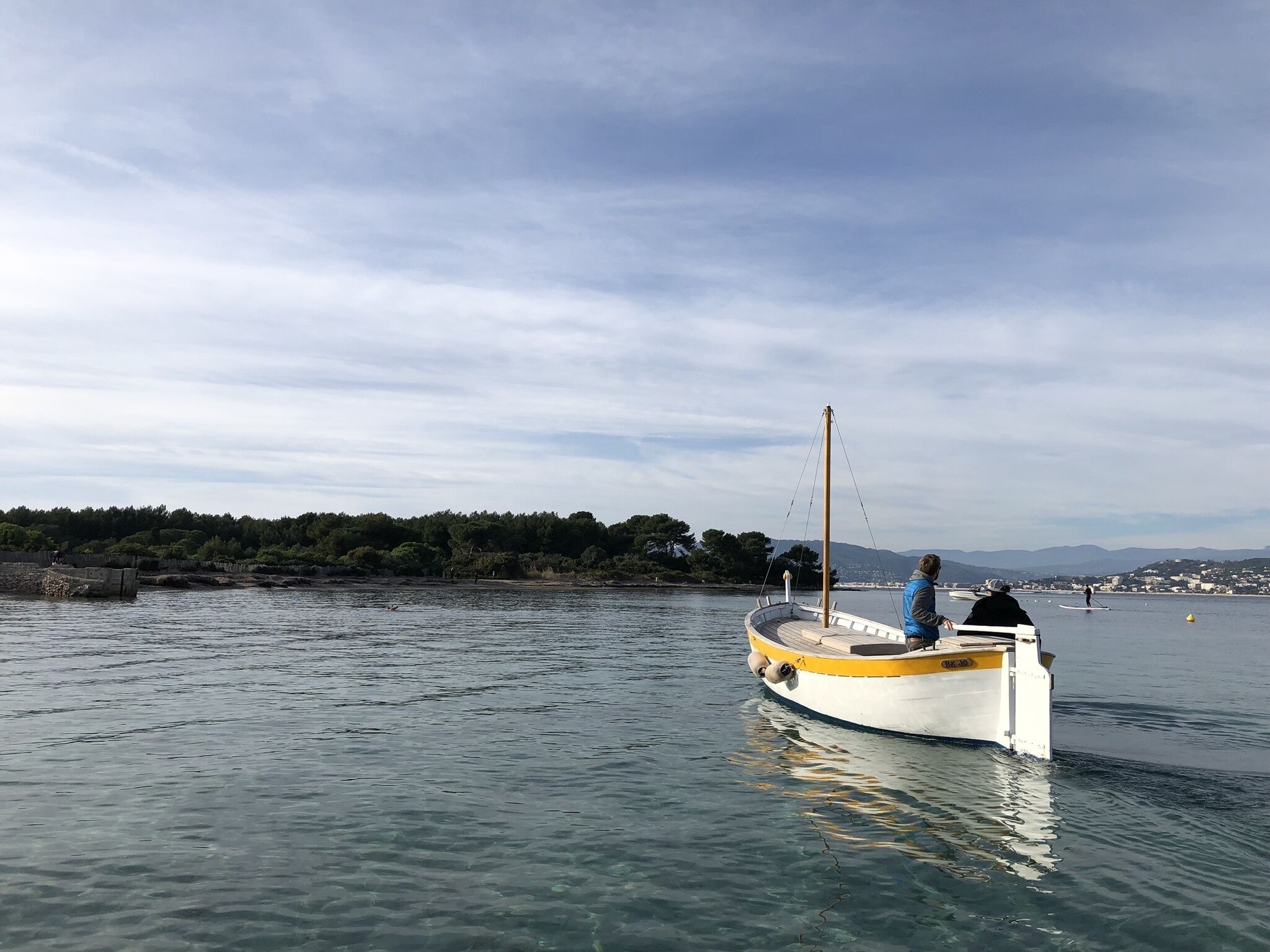 A small boat on calm water with a person paddling.