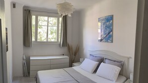A bedroom with a large bed, a bedside table, a nightstand, a window with curtains, a radiator, and a wall-mounted artwork. - CANNES +++ PERFECT FOR CONGRESS AND TOURISM (Cannes)