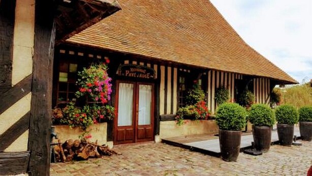 A traditional building with a thatched roof, wooden beams, and a sign reading "Hotel Paul Paard". There are potted plants and a wooden fence in front.