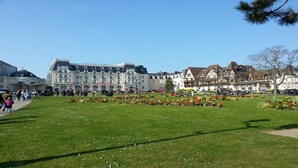 A Grand Hotel with a large building, a well-maintained lawn, and flower beds.