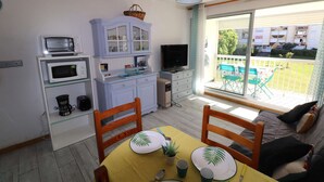 En kompakt opholdsstue med spiseplads, tekøkken og balkon med udsigt.