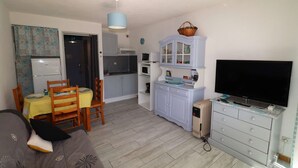 En kompakt bolig med tekøkken, spiseplads og et fjernsyn.