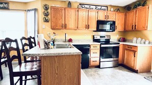 A kitchen with wooden cabinets, a granite countertop, a microwave, an oven, and a sink.