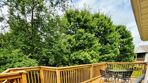 A wooden deck with a table and chairs, surrounded by trees.