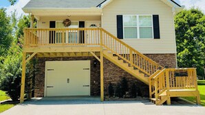A two-story house with a covered front porch, a stone foundation, and a garage.