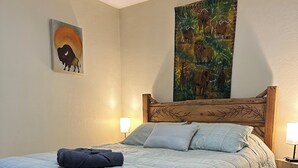 A bedroom with a bed, a wooden bench, two wall-mounted lamps, and two paintings. - Tahoe house with amazing mountain views (South Lake Tahoe)