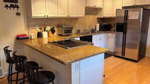 A kitchen with white cabinets, a granite countertop, a stainless steel refrigerator, a toaster, and a dishwasher. - Tahoe house with amazing mountain views (South Lake Tahoe)