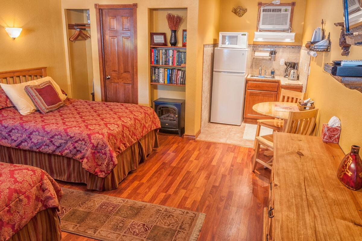 Un dormitorio con una cama grande, un aparador de madera, una mesita pequeña y una estantería.